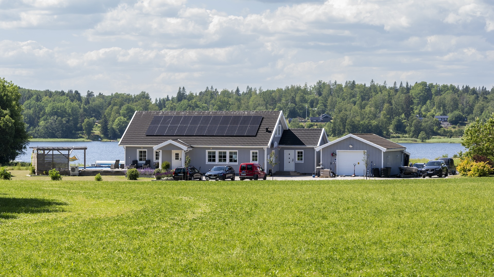Bild på villa med solceller på taket, sjö i bakgrunden.