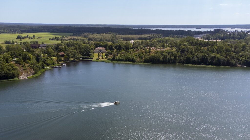Bild på landskap över sjö med en motorbåt