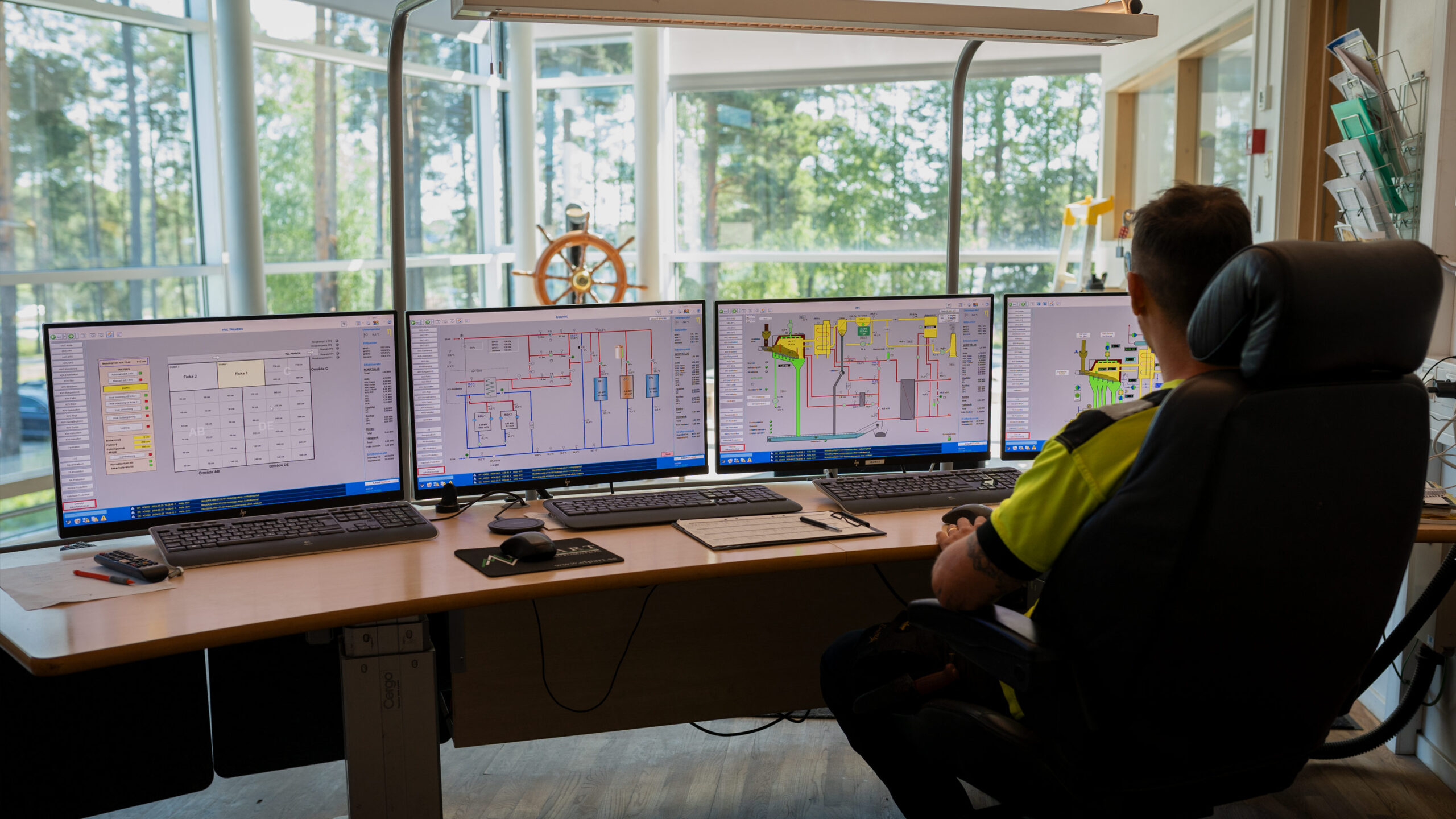Bild från kontrollrum på Arsta fjärrvärmeverk, en man med fyra skärmar där han kontrollerar fakta och ser hur kraftvärmeverket fungerar i realtid.
