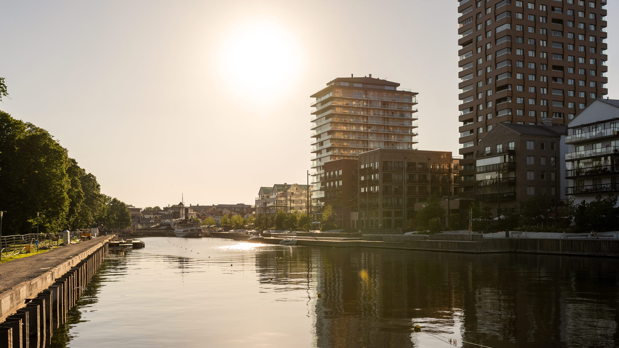 Bild på fastigheter med fjärrvärme. Solig vy över kaj, vattendrag och moderna höghus i stadsmiljö i Norrtälje.