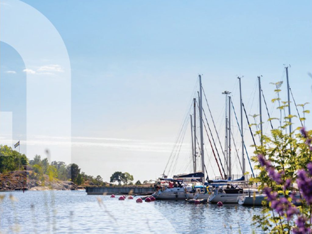 Del av framsidan av Norrtälje Energis årsredovisning och hållbarhetsrapport för 2024. Omslaget har en ljusblå himmel med vit text och en bild av en småbåtshamn med segelbåtar förtöjda vid bryggan.