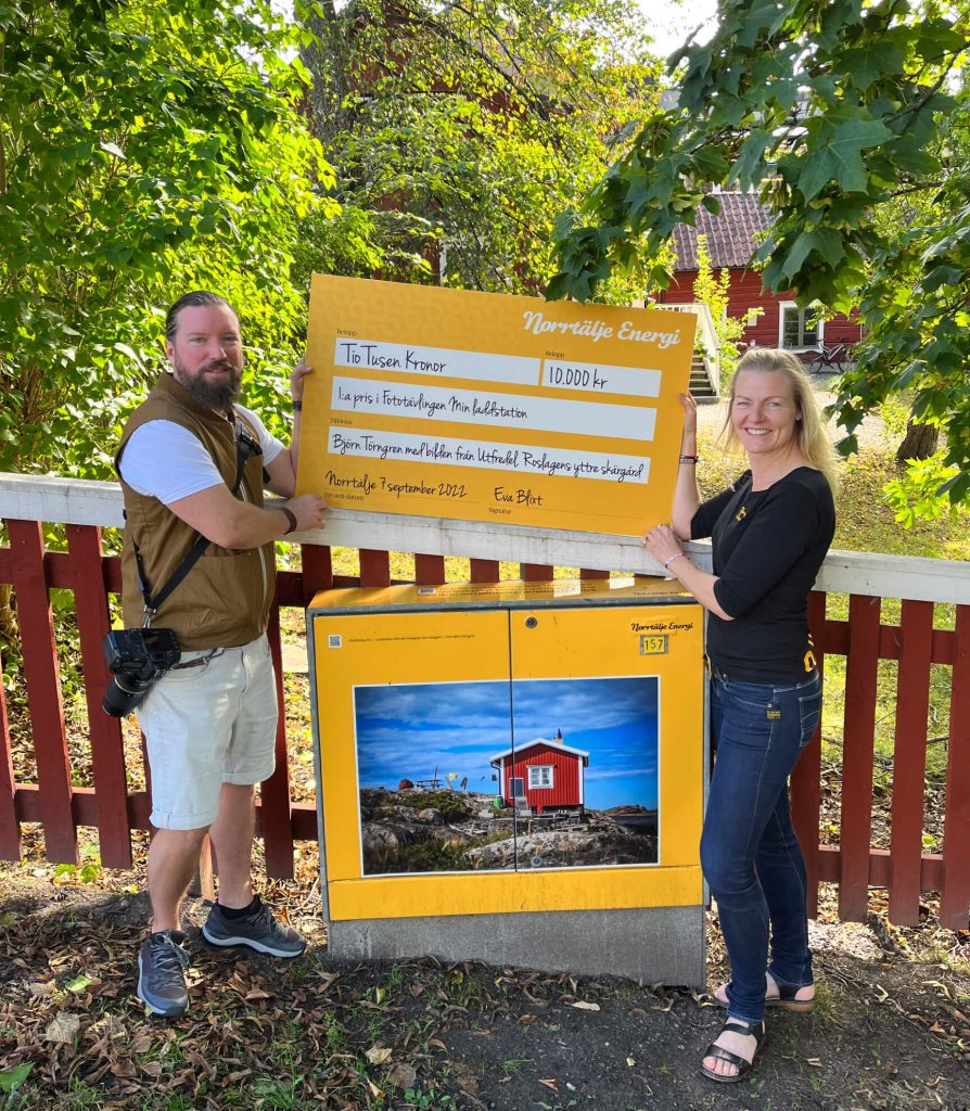 Björn (vinnare) och Eva, chef Norrtälje Energi med en check på 10.000 kr, fototävling "Min laddstation".