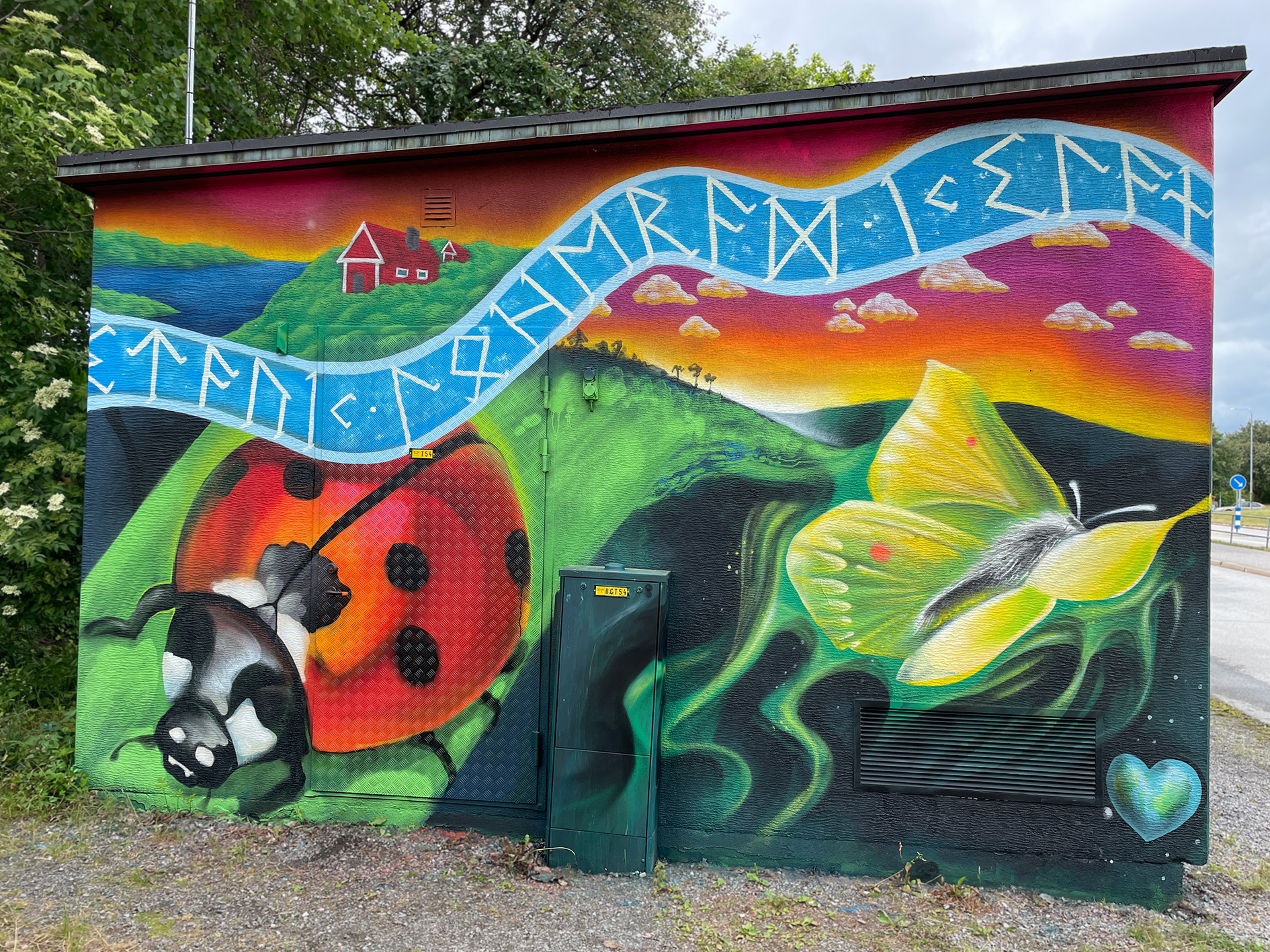 Nyckelpiga och gul fjäril bland gröna kullar i solnedgång.