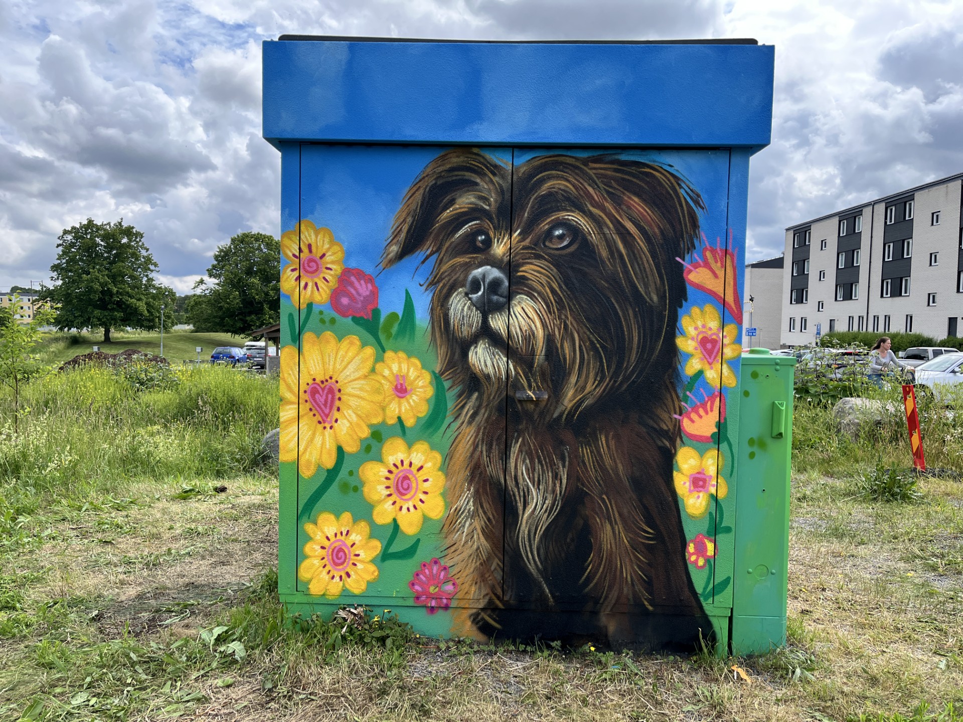 En elnätsstation är målad med färgglad gatukonst som föreställer en hund.