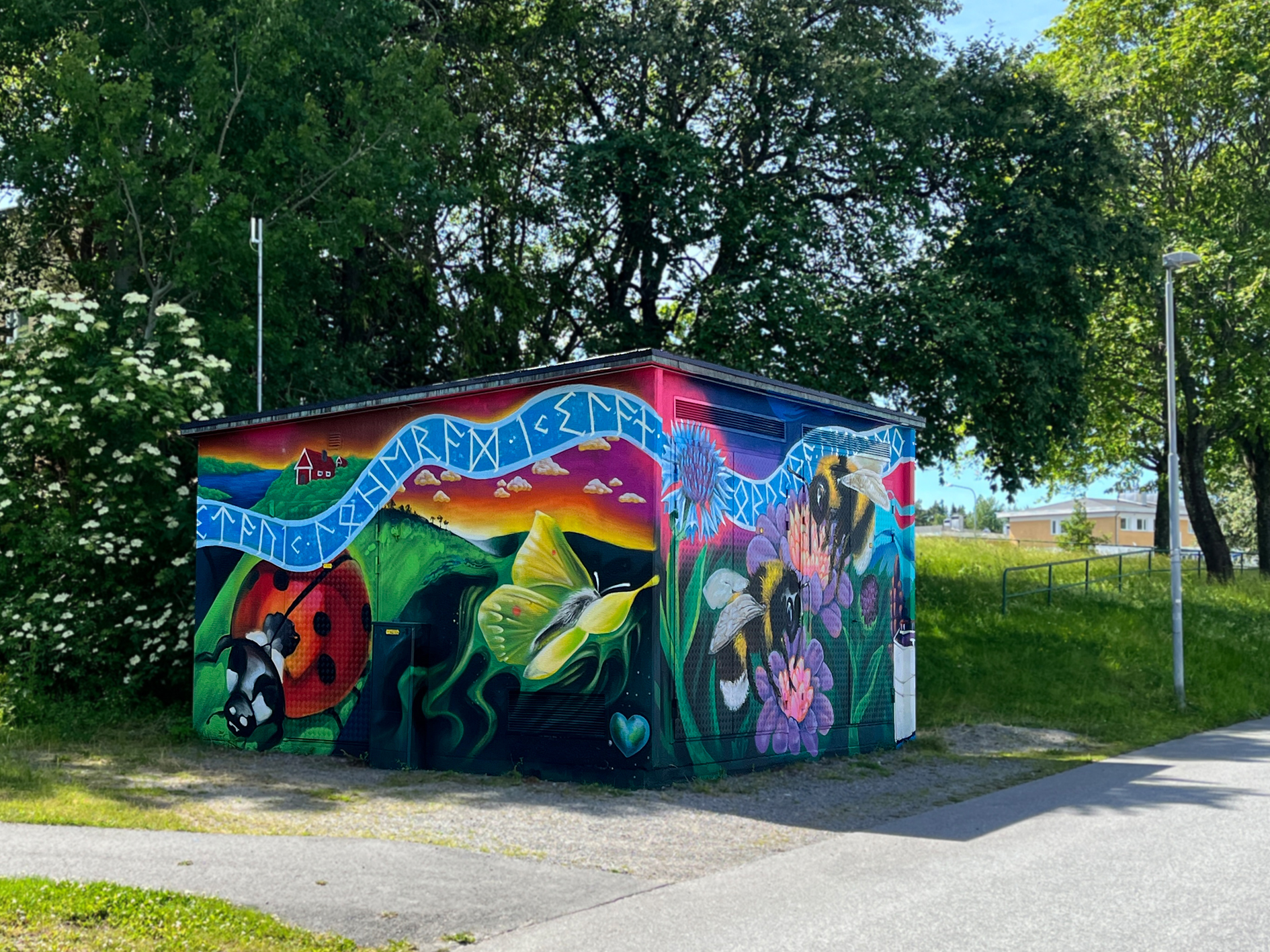 Nätstation målad med färgglada motiv av nyckelpiga, fjäril, humlor och blommor.