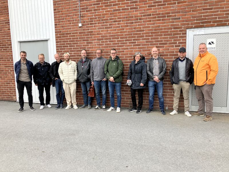 Grupp framför tegelvägg.