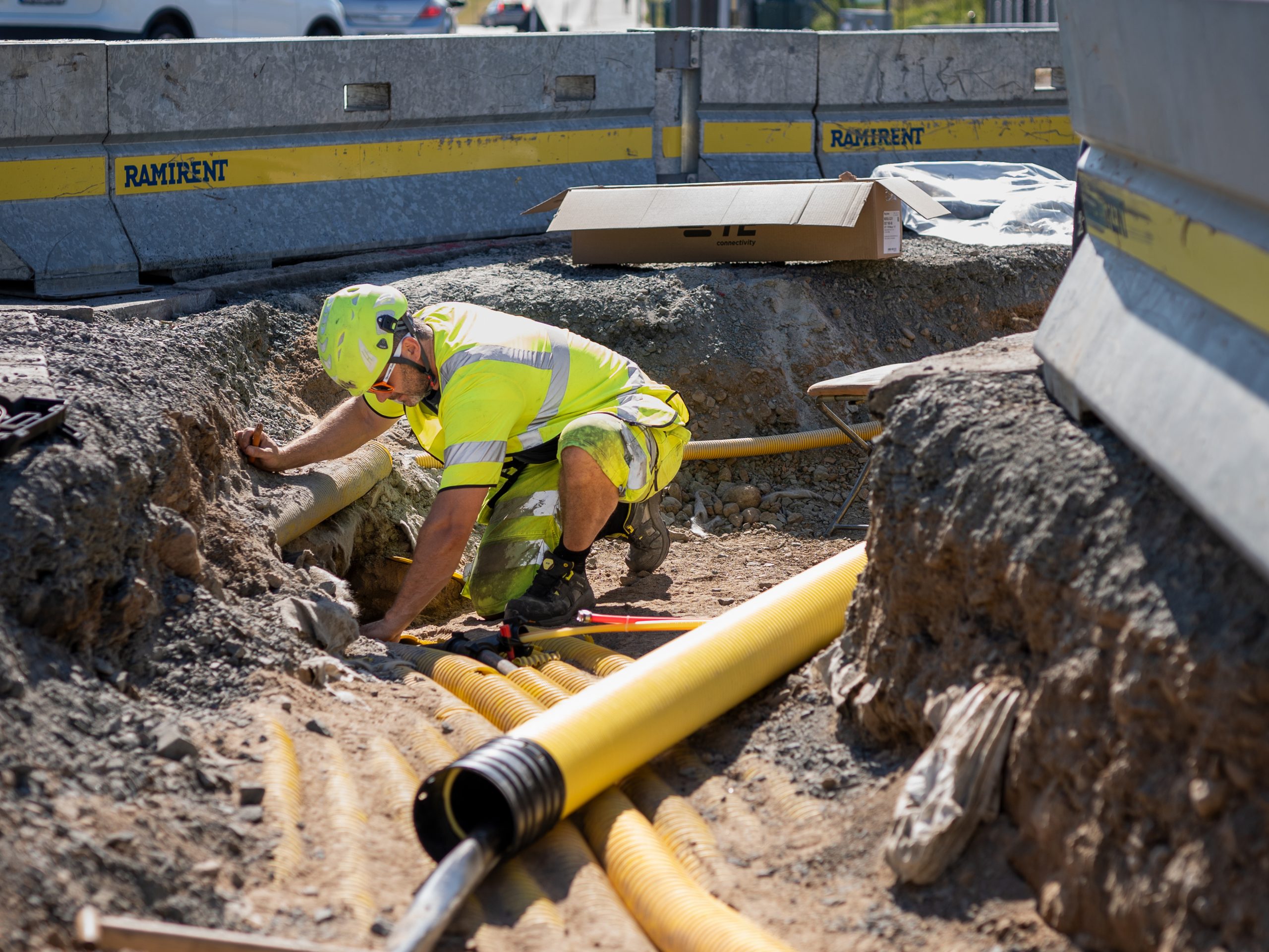 Norrtälje Energi-arbetare i varselkläder arbetar i ett schakt med rör och verktyg.