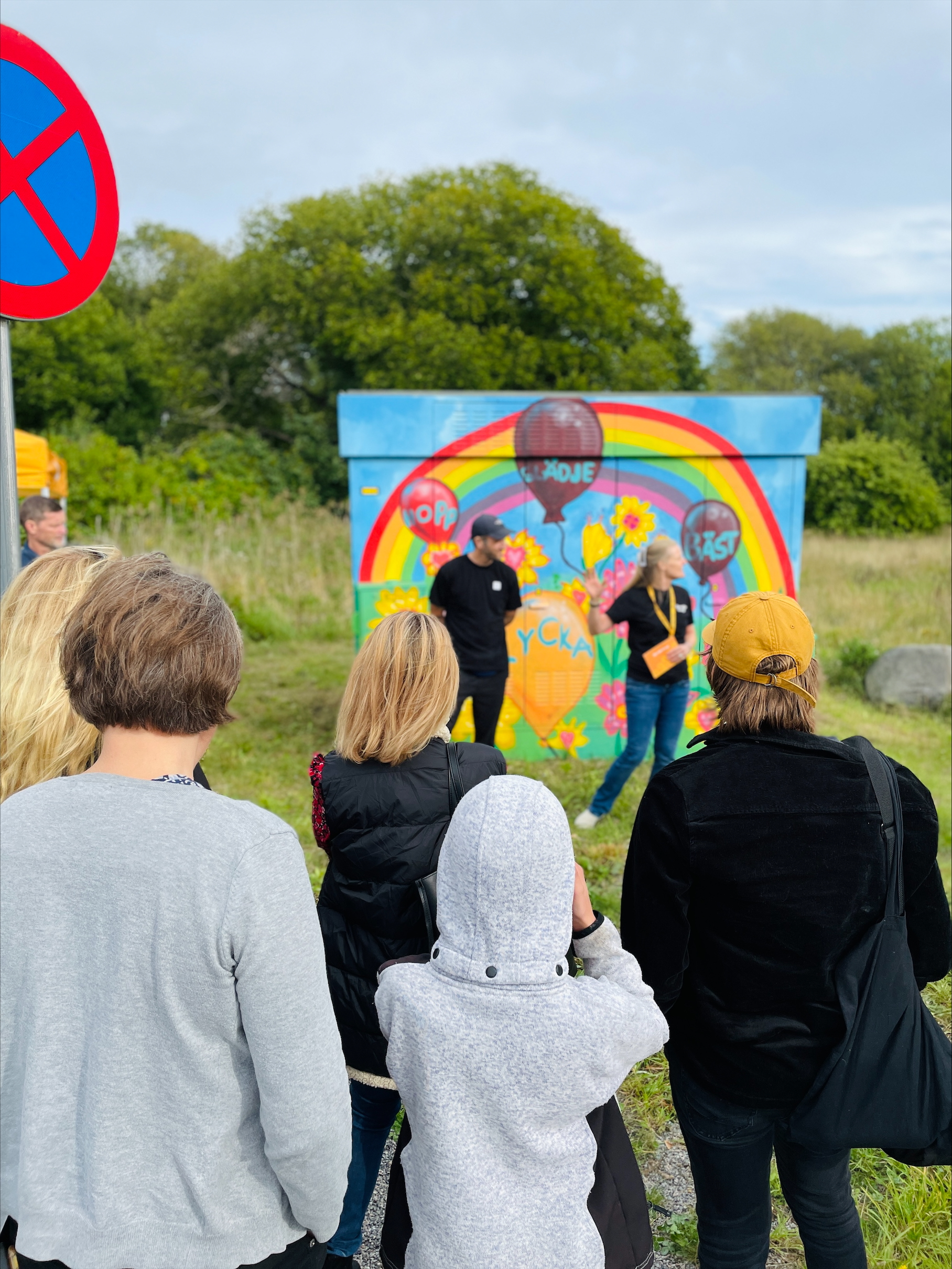 Publik framför färgglad muralmålning vid invigning utomhus.