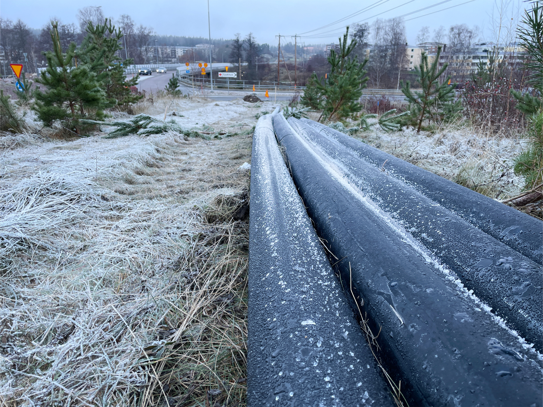 Frosttäckta el- och fiber­rör ligger utlagda i ett gräsområde vid Västra vägen.