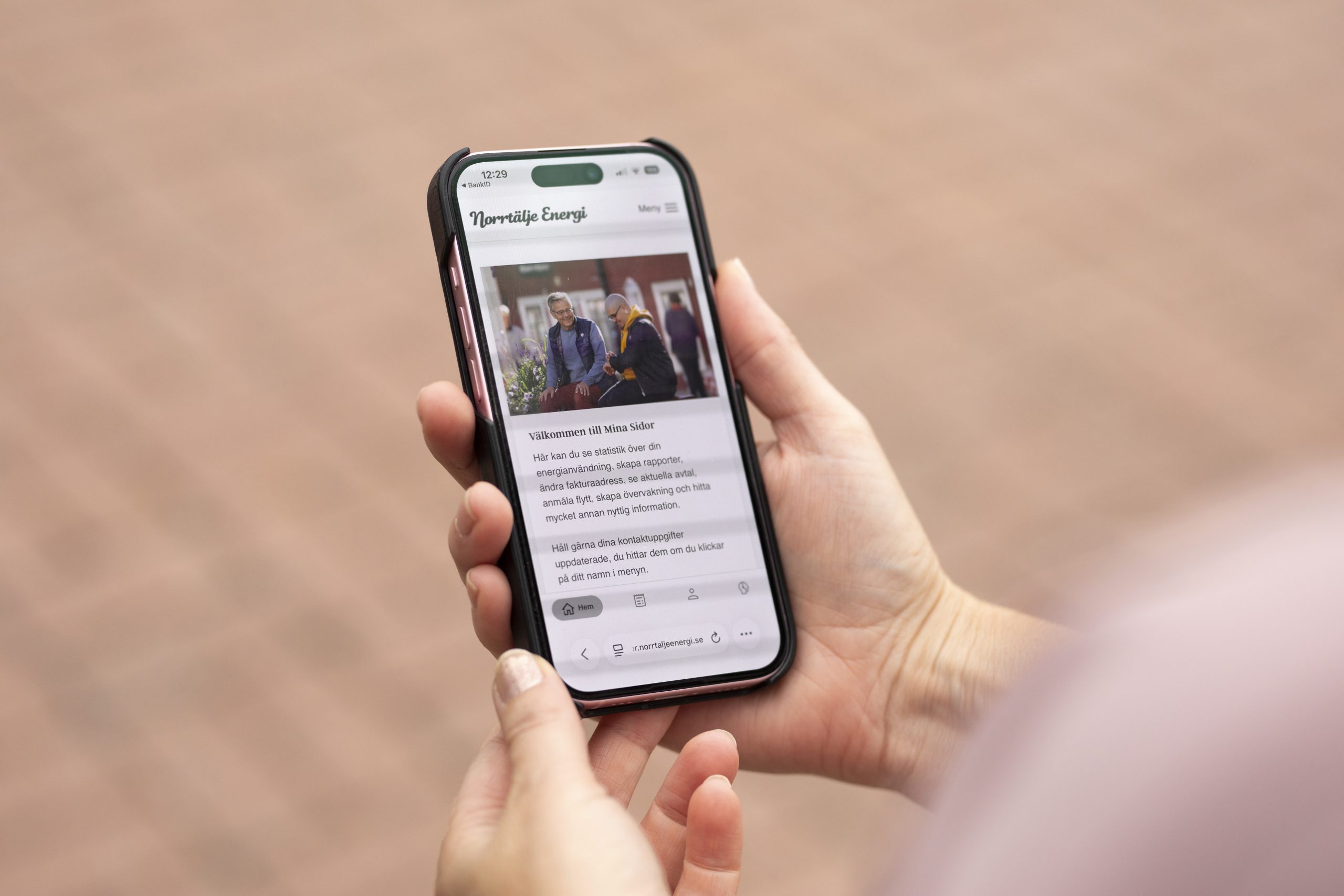 Person håller en mobil som visar Norrtälje Energis sida Mina sidor.