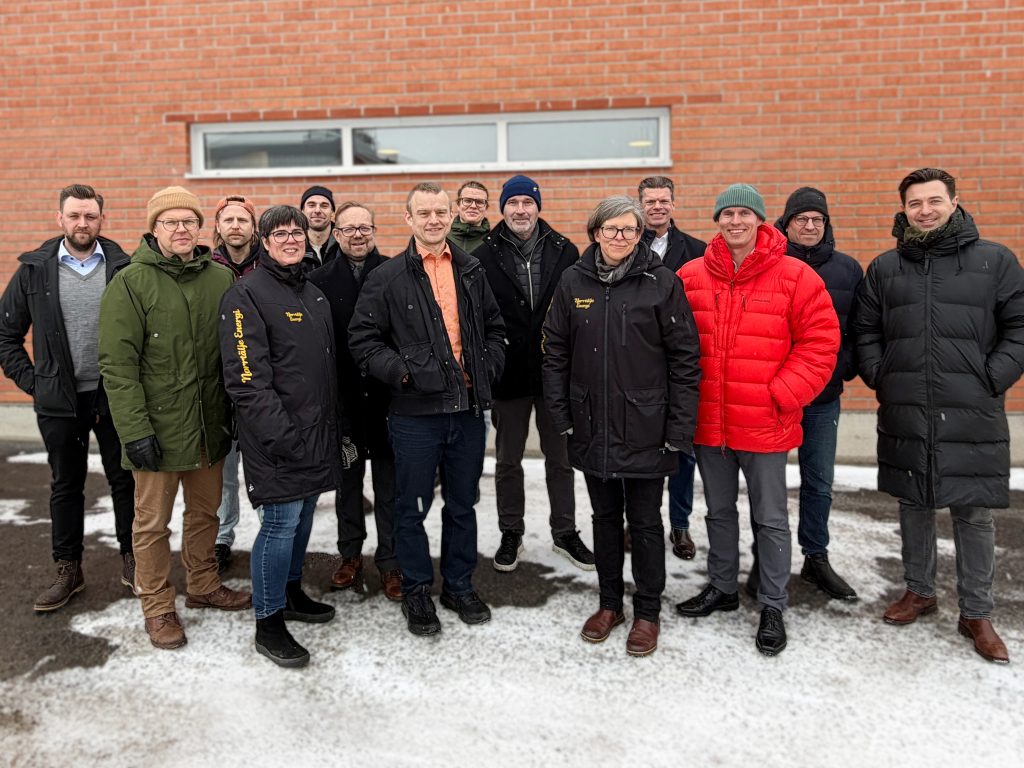 Grupp personer i vinterkläder framför tegelvägg utomhus